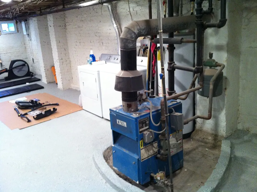 Blue cast iron boiler with its flue pipe and copper piping in a home basement