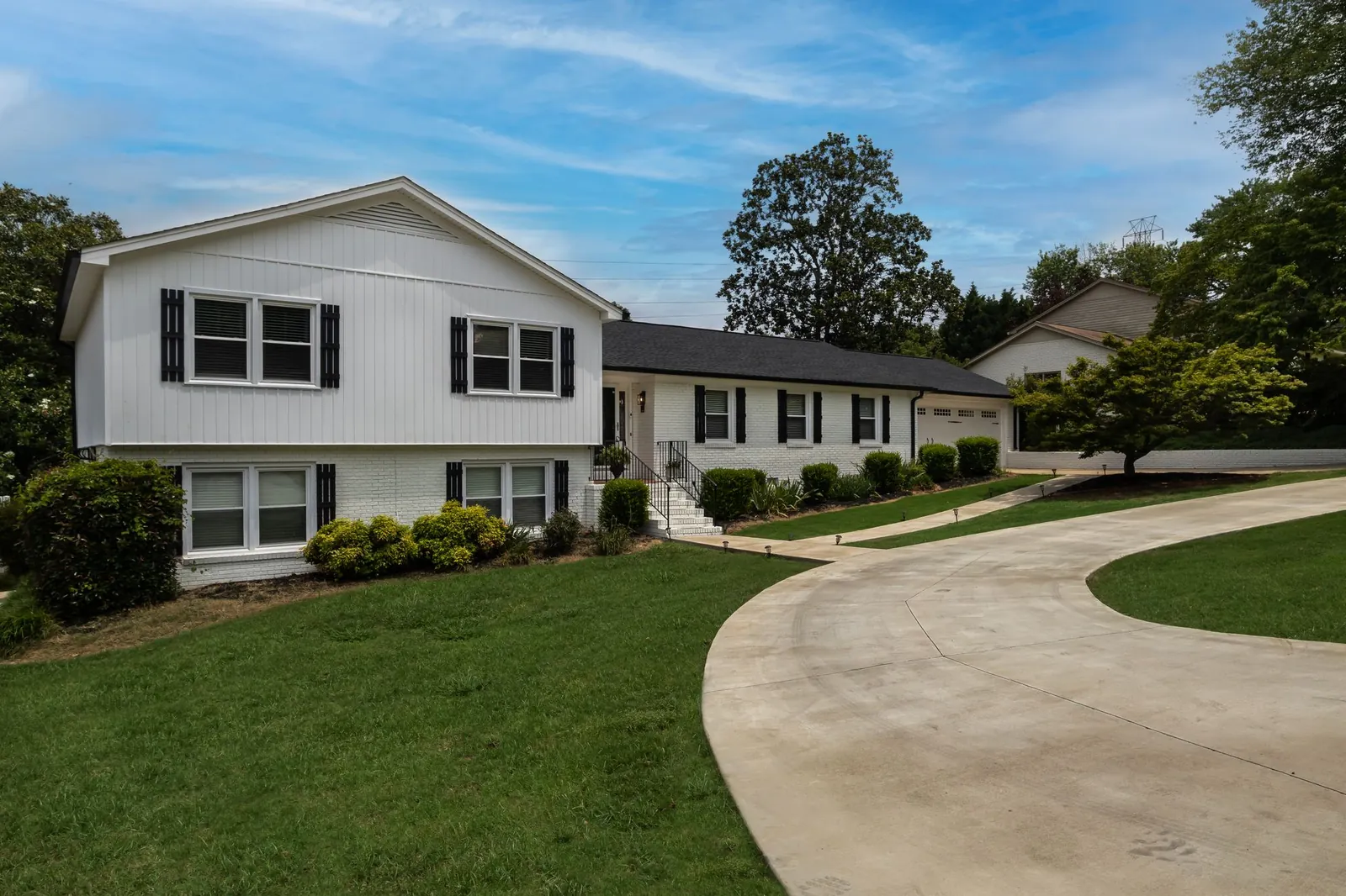 Split-level house with a wide lawn and curved driveway in a suburban neighborhood